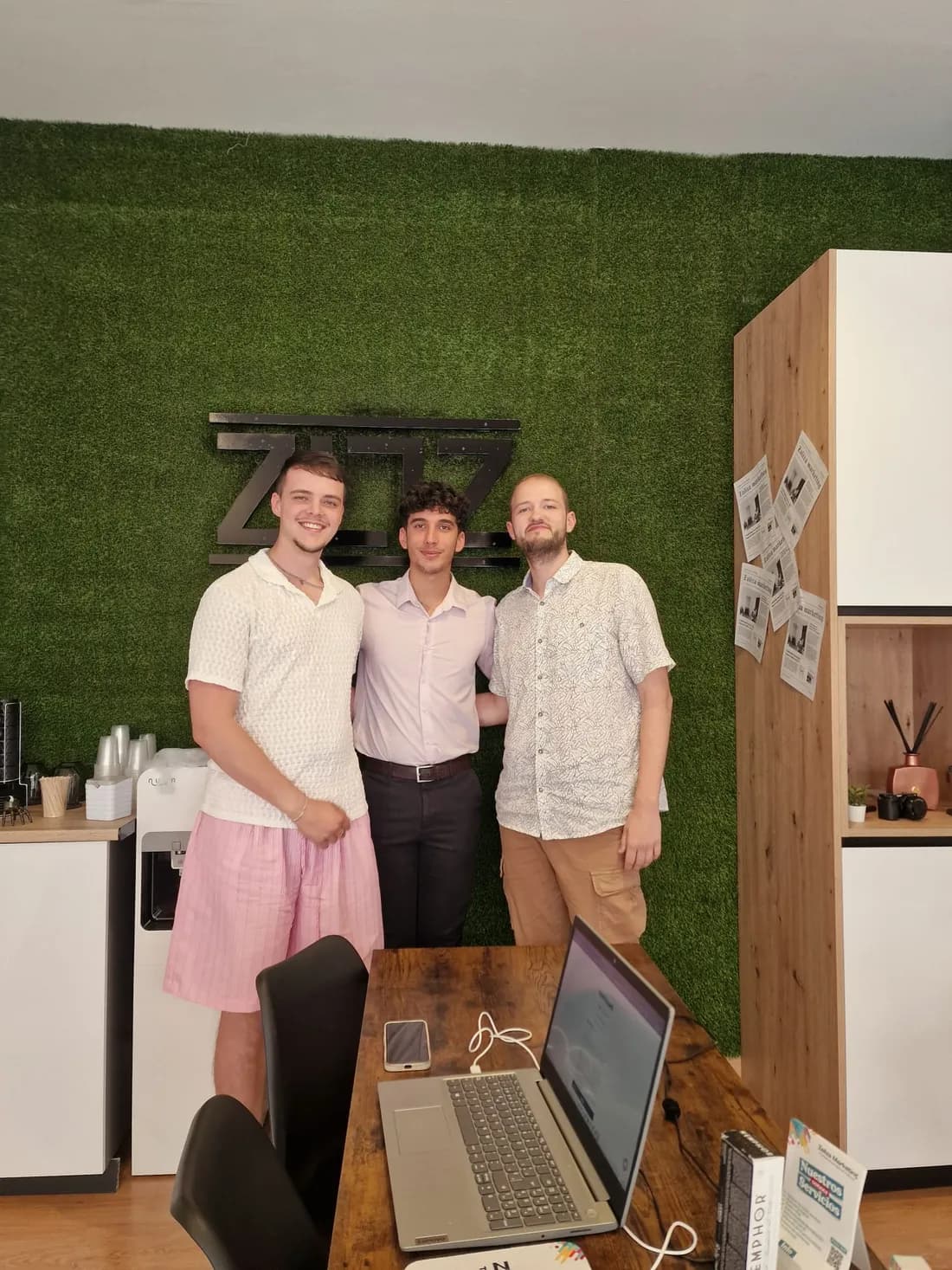 Three members of the Zaliza Marketing team in the Alhaurín de la Torre office, in front of the agency logo